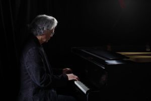 man with white hair playing piano