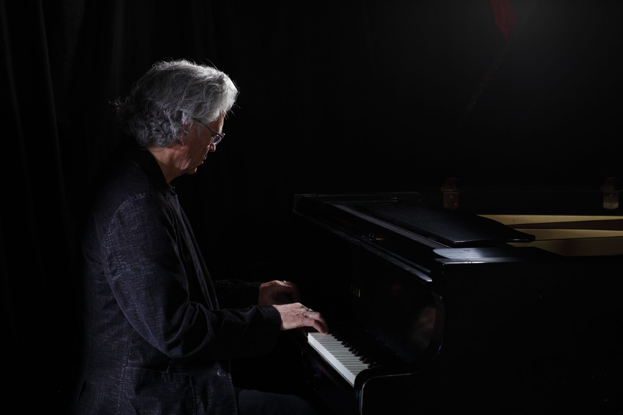 A man playing piano in the dark.