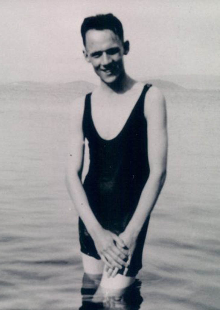 A man in a bathing suit standing on the beach.